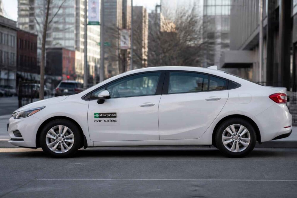 Biały sedan Enterprise Car Sales na ulicy miasta Biały sedan Enterprise Car Sales zaparkowany przy miejskiej ulicy wśród wysokich budynków