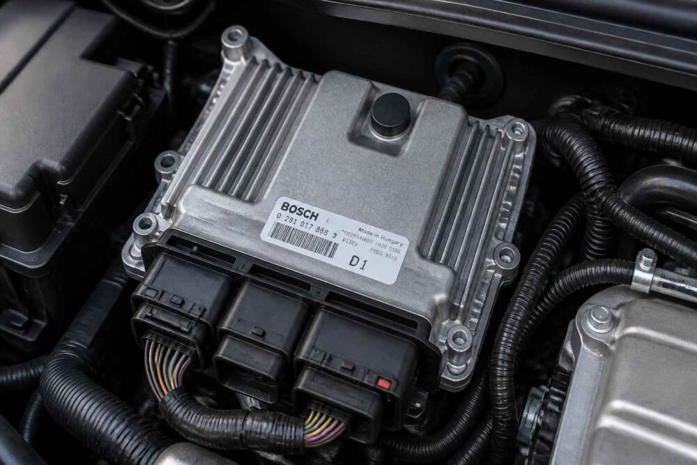 Moduł sterujący Bosch w komorze silnika Elektroniczny moduł Bosch z wiązką przewodów zamontowany w komorze silnika samochodu