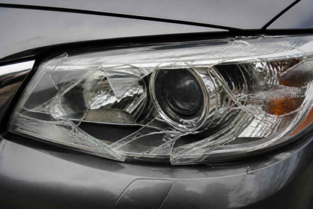 Pęknięta lampa przednia samochodu Zbliżenie na rozbitą przednią lampę w szarym samochodzie