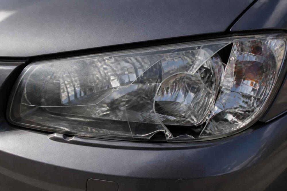 Zbliżenie na pęknięty przedni reflektor w srebrnym samochodzie