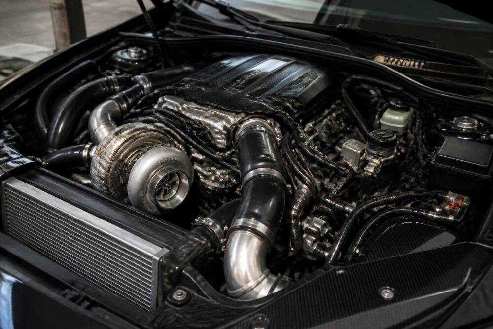 Zmodyfikowany silnik z widoczną turbosprężarką Otwarta komora silnika z dużą turbosprężarką, przewodami dolotowymi i aluminiowym intercoolerem
